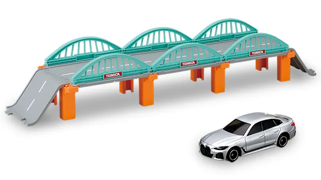 Tomica World 長大鐵橋組官方商品照，綠色拱橋配橘色橋墩，旁邊是銀色 BMW i4